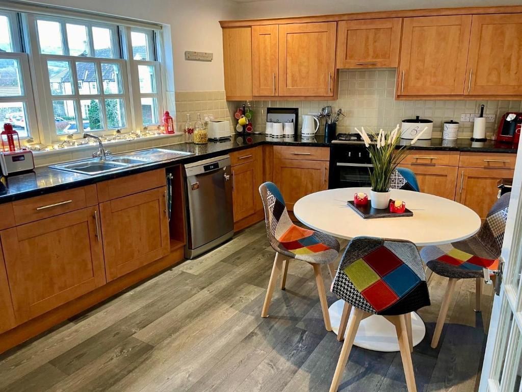 a kitchen with wooden cabinets and a table and chairs at The Gorge Getaway - Deluxe 3-Bedroom Apartment in Cheddar