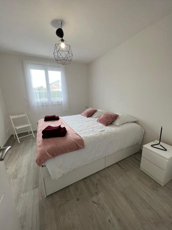 Un dormitorio blanco con una cama grande y una ventana en le Rocher, en La Plaine-sur-Mer