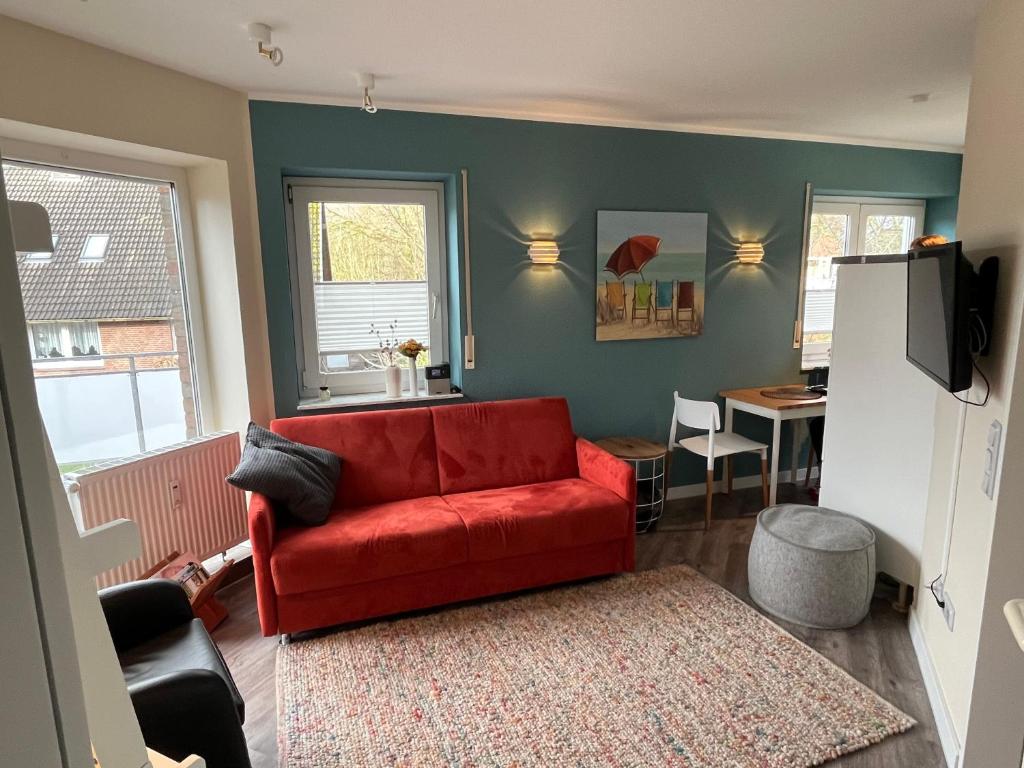ein Wohnzimmer mit einem roten Sofa und einem Tisch in der Unterkunft Rosenhus 5 in Horumersiel