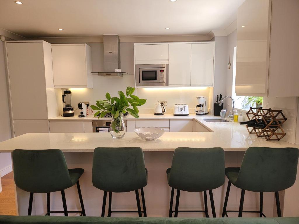 a kitchen with a island with four green chairs at Three Bedroom Apartment by Beautiful Park in London