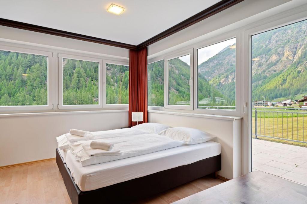 een slaapkamer met een bed in een kamer met ramen bij International House Sölden Studio mit Bergblick ZW 1 in Sölden