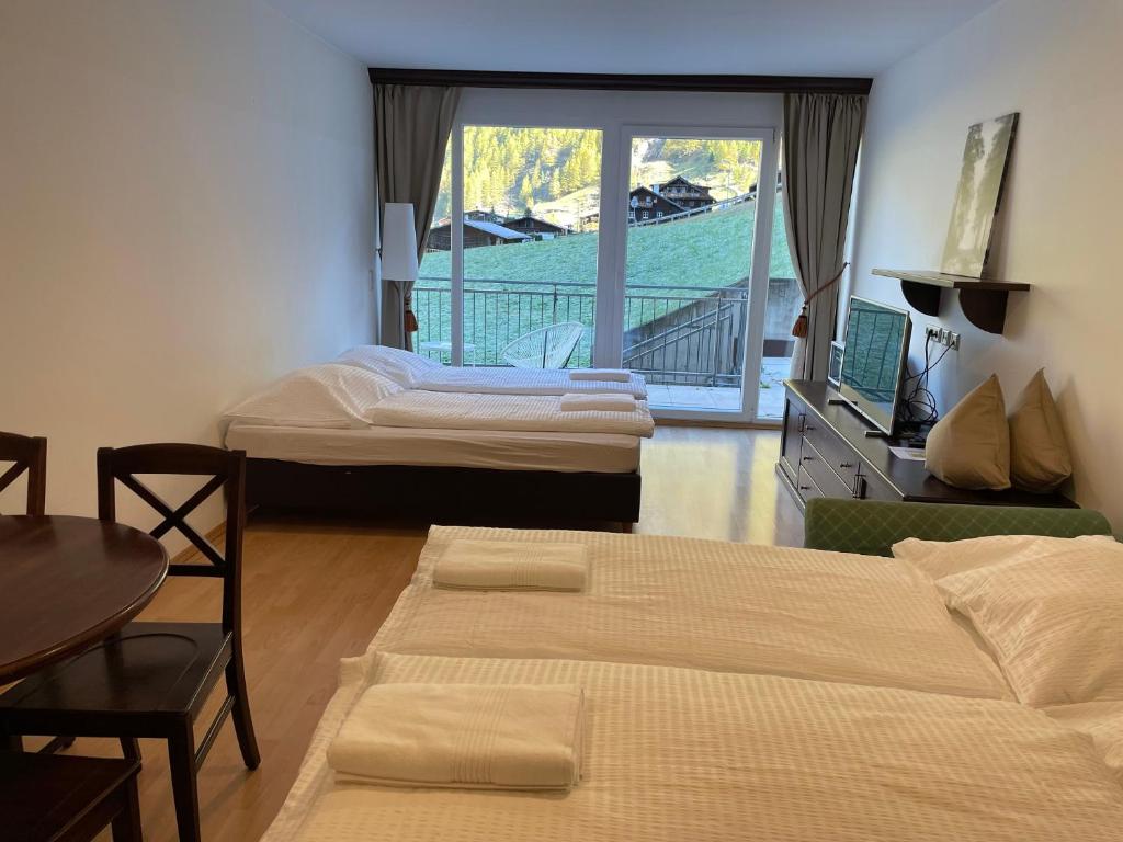 a room with two beds and a table and a balcony at International House Sölden Studio ZW 5 in Sölden