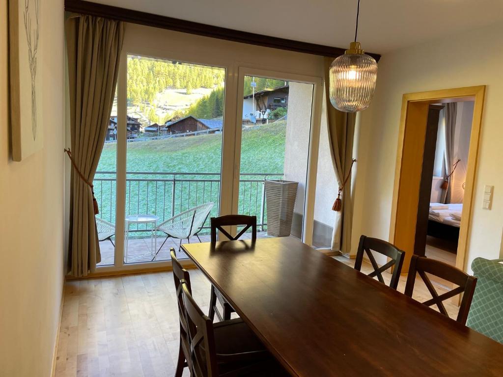 ein Esszimmer mit einem Tisch und einem großen Fenster in der Unterkunft International House Sölden Deluxe Apartment ZW 13 in Sölden