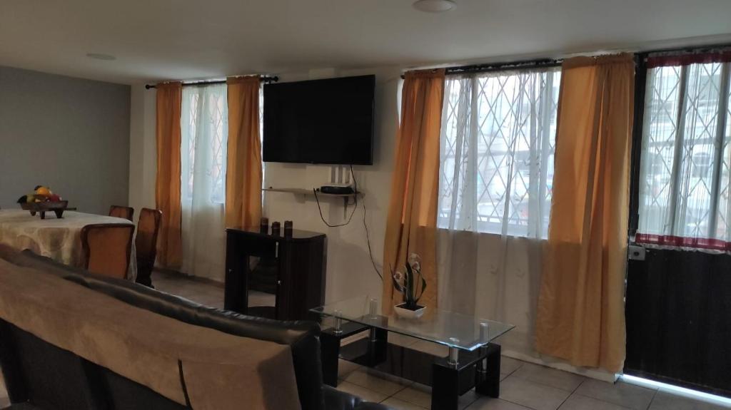 sala de estar con TV de pantalla plana y cortinas en Casa Cuenca en Cuenca