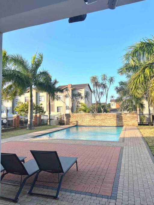 2 sillas sentadas junto a una piscina en Seasons Court umhlanga 2bed Apt, en Durban