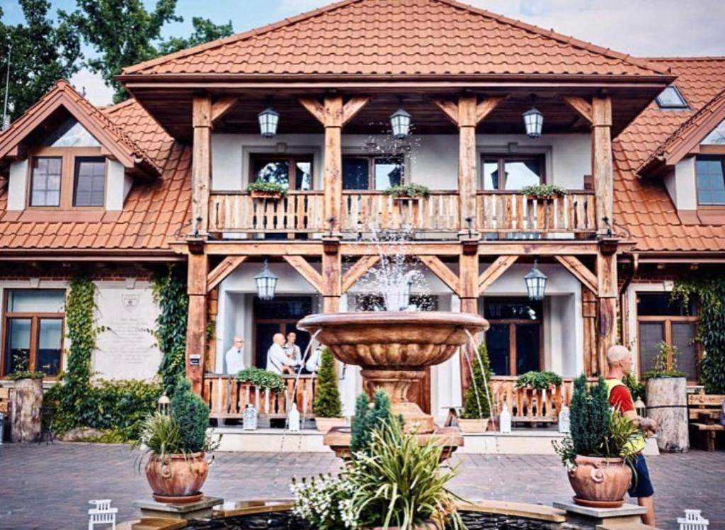 une grande maison en bois avec une fontaine en face de celle-ci dans l'établissement Dwór Sulejów, 