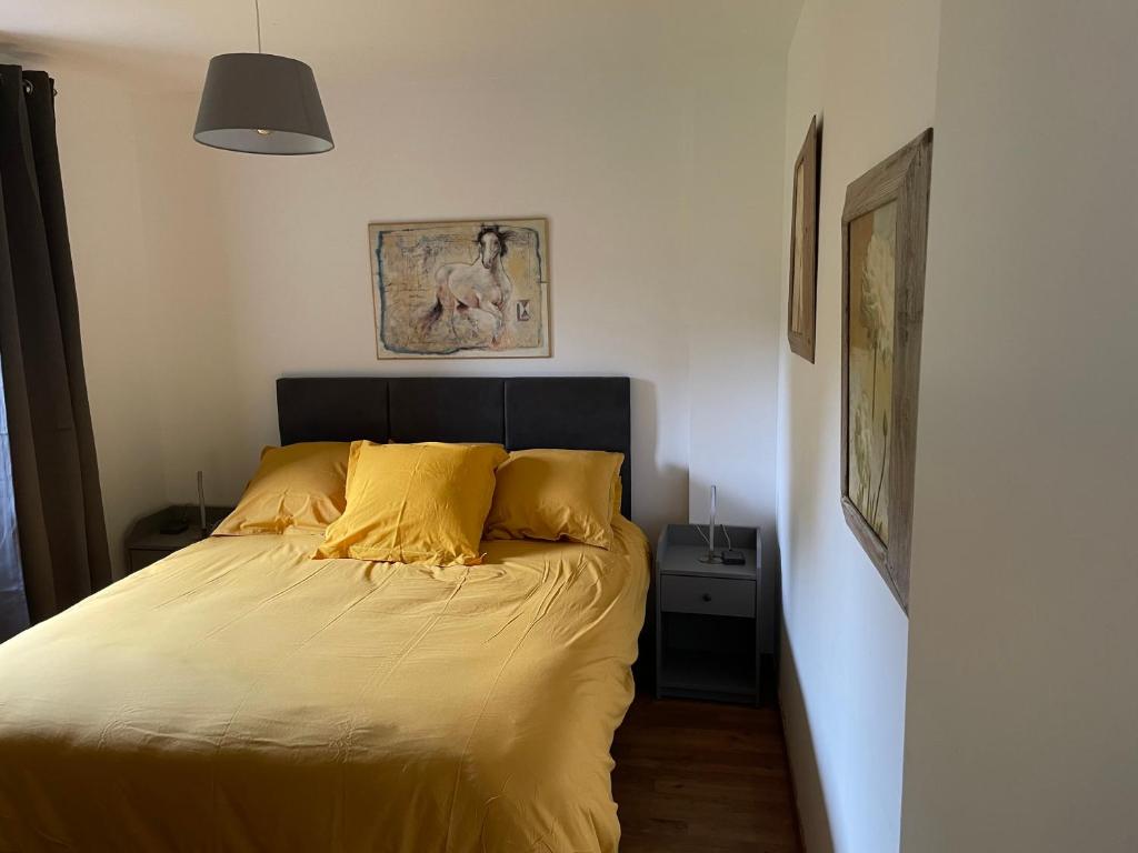 een bed met gele lakens in een kleine slaapkamer bij Le Courtil in Cerisy-la-Forêt