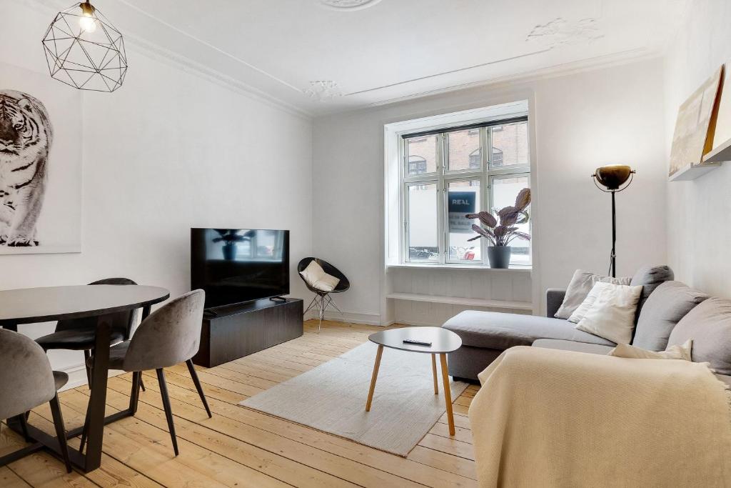 een witte woonkamer met een bank en een tafel bij Perfectly located cozy apartment in Kopenhagen