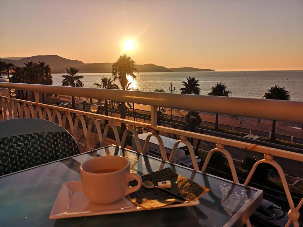 尼斯的住宿－Beach front, Superbe appartement pour 4 personnes，一边在桌子上一边享用咖啡一边欣赏海景