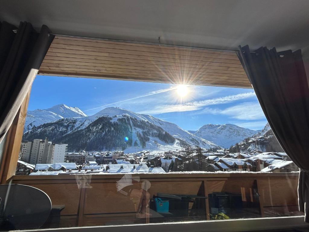 een raam met uitzicht op een met sneeuw bedekte berg bij Le Portillo in Val dʼIsère