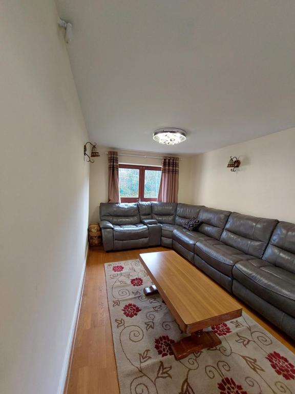 a living room with a leather couch and a coffee table at Dobcross Close in Manchester