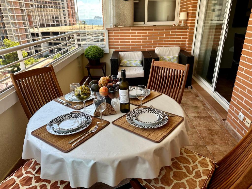 una mesa con platos y una botella de vino en el balcón en Benimar 1, en Cala de Finestrat