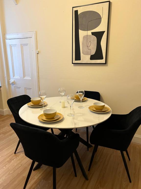 a white table with chairs and plates and wine glasses at Corner House 51 Go Go Street Ground Floor Largs KA308JW 2 Bedroom in Largs