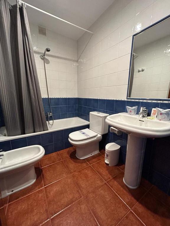 a bathroom with a toilet and a sink and a tub at Hotel Restaurante el Fornon in Novellana