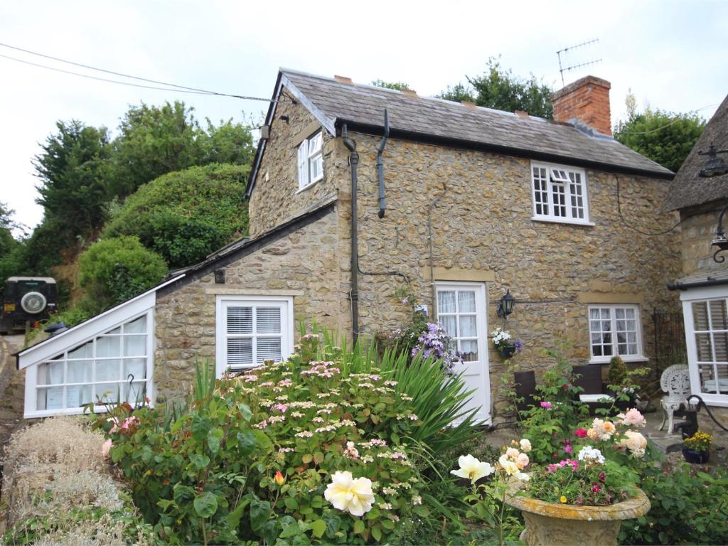 an old stone house with flowers in front of it at 1 Bed in Burton Bradstock DC178 in Burton Bradstock