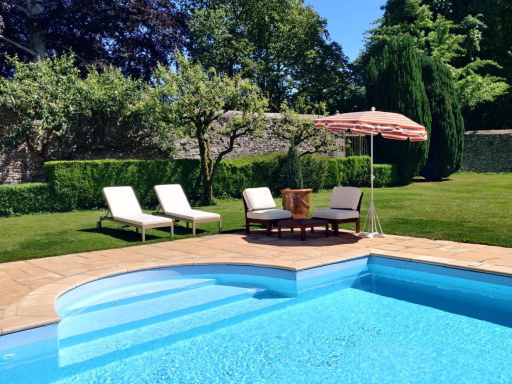 een zwembad met 2 stoelen en een parasol bij Holiday Home Château de Boucéel Mont Saint Michel in Vergoncey