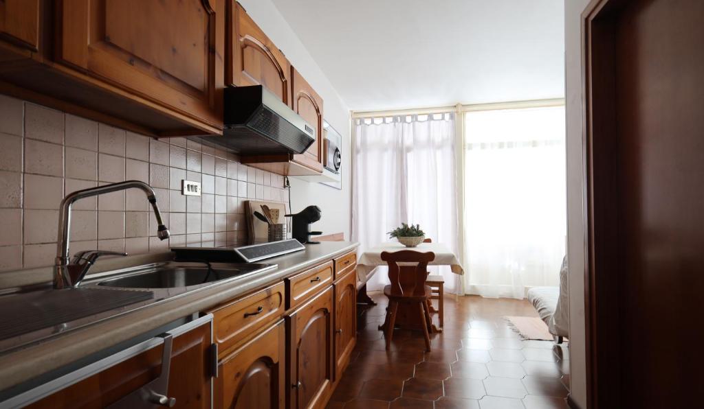 a kitchen with wooden cabinets and a sink and a window at Mountain Apartment Rododendro in Tarvisio