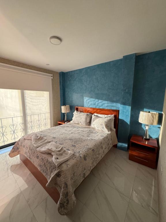 een slaapkamer met een bed en een blauwe muur bij GALASUITES in Puerto Baquerizo Moreno