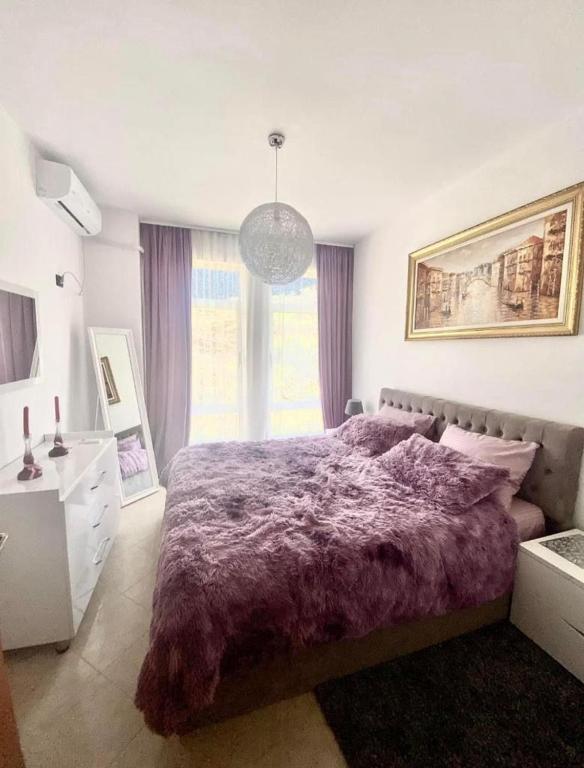 1 dormitorio con cama morada y ventana grande en Holiday apartment, en Durrës