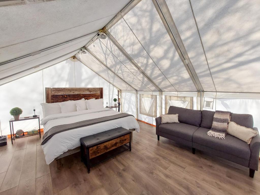 a bedroom in a tent with a bed and a couch at Gateway Glamping in Gateway