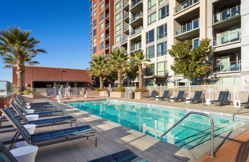 a swimming pool with lounge chairs and a building at Global Luxury Suites San Jose Downtown in San Jose