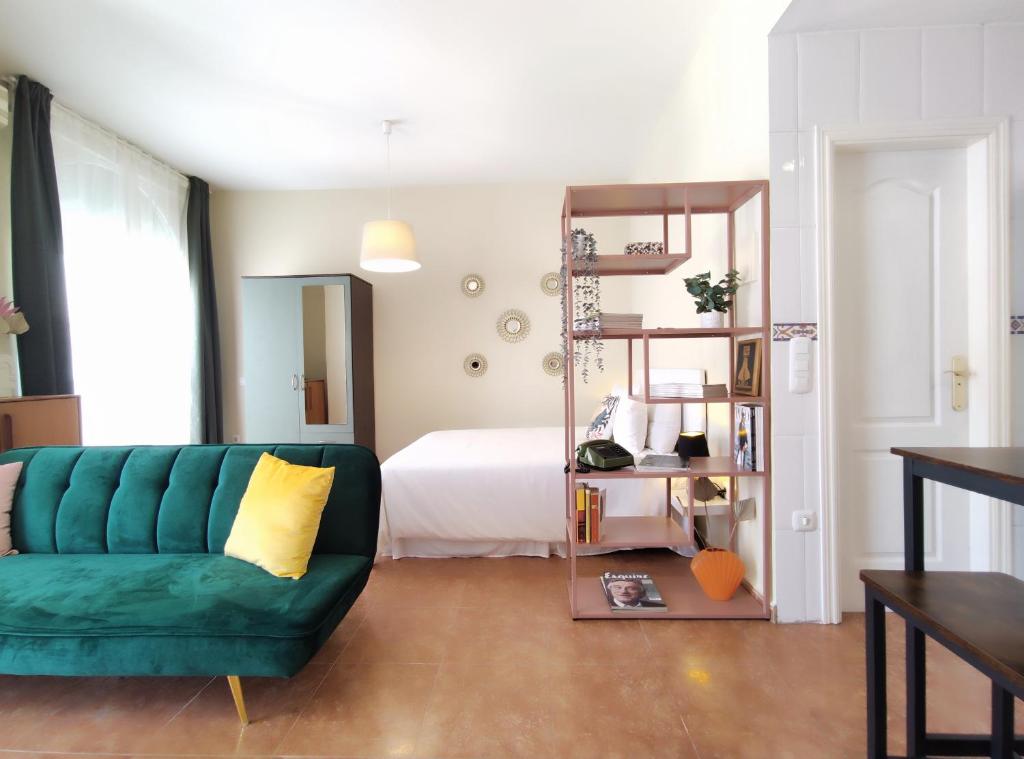 sala de estar con sofá verde y cama en Bonito y acogedor estudio - Nice and cozy studio, en Málaga