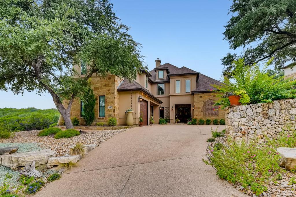 a large house with a stone wall and a driveway at * Luxury 4500 sf home* Pool Spa * near Lake Austin in Austin