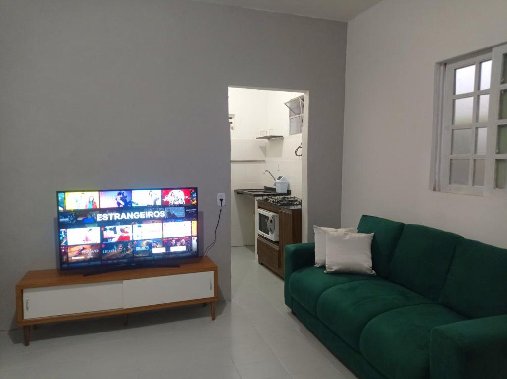 sala de estar con sofá verde y TV de pantalla plana en Kitnet Mobiliada en Camaçari