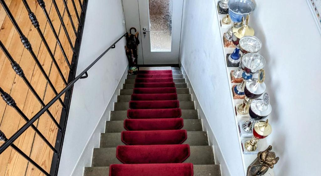 una escalera con suelo de moqueta roja con placas en la pared en Private Bedrooms Geneva, en Ginebra