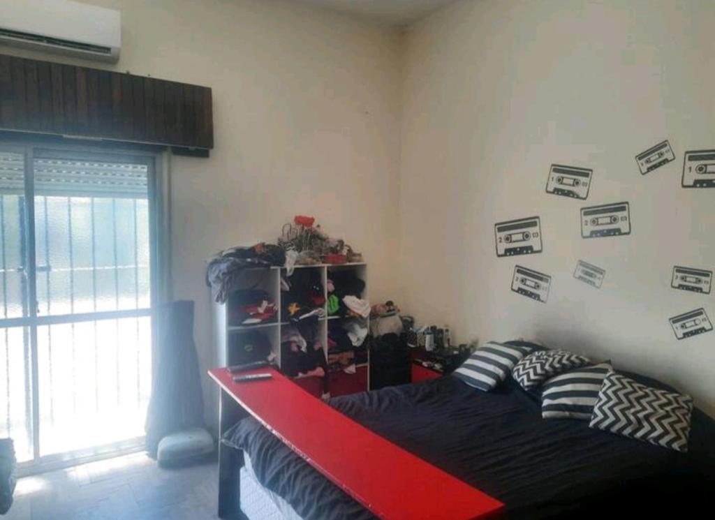 a bedroom with a bed with a red frame and pictures on the wall at Pink house in Buenos Aires