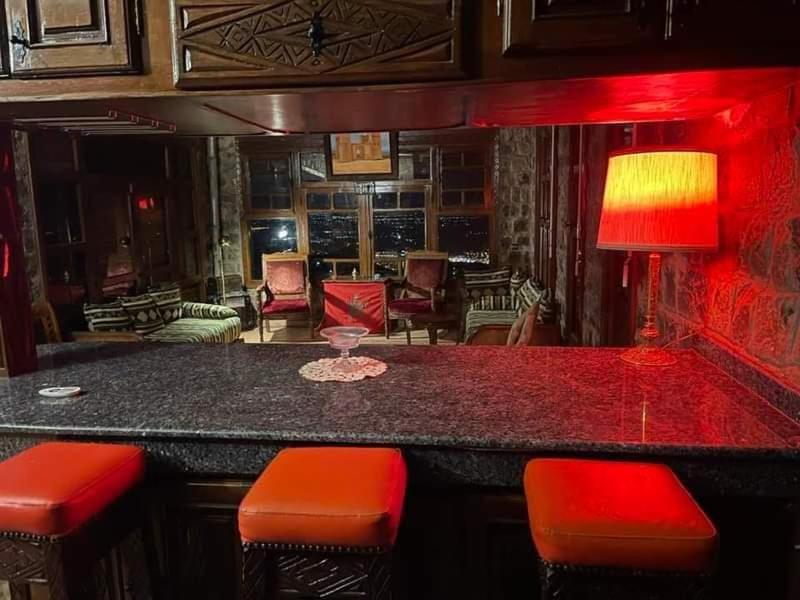 a bar with red stools in a living room at Chalet kaddoum in Beni Mellal