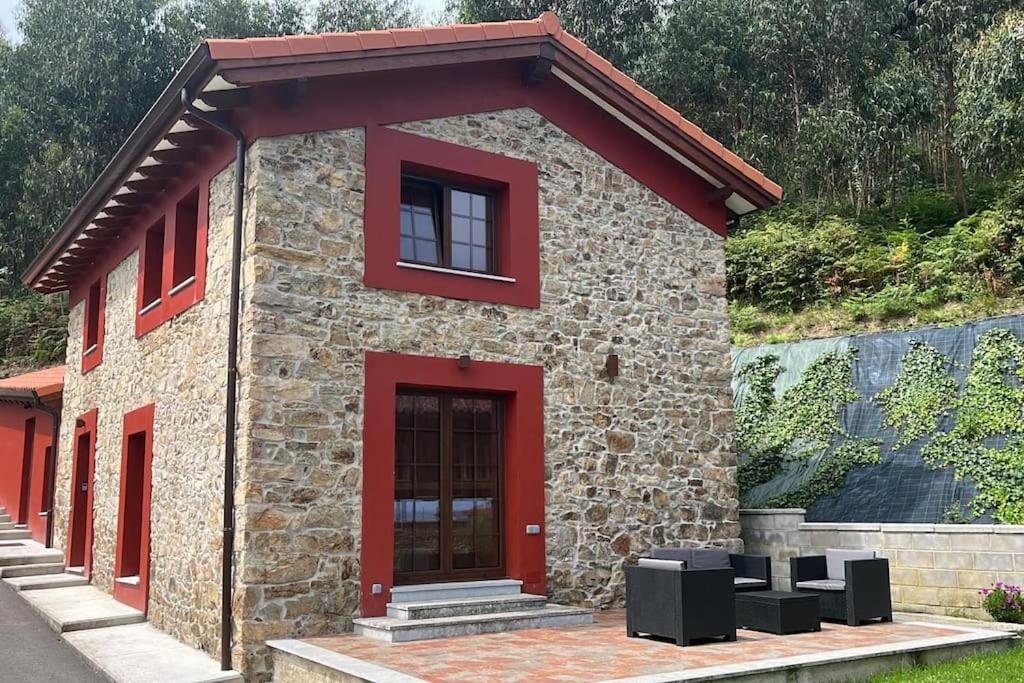 een klein stenen gebouw met een rode deur bij La Casa del Marinero in Cudillero
