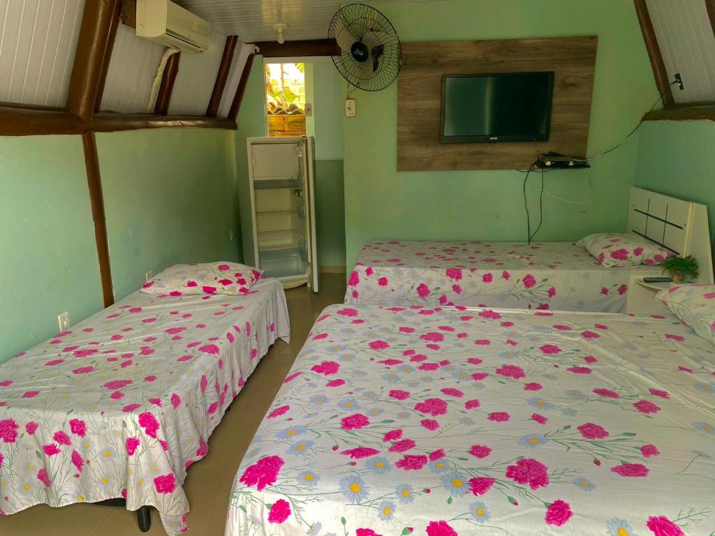 two beds in a room with pink flowers on them at Marcelo Chale in Paraty