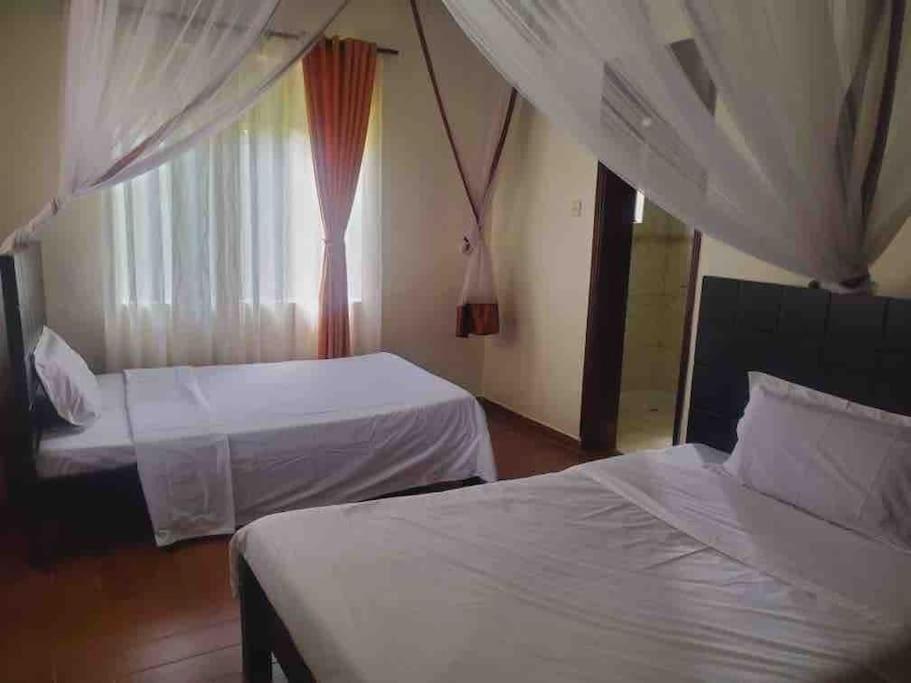 a hotel room with two beds and a window at Reverie Villa in Mutungo