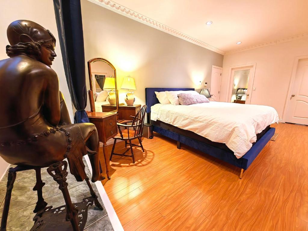 a bedroom with a statue of a woman sitting in a chair at Artful Retreat: Modern Mansion in Surrey