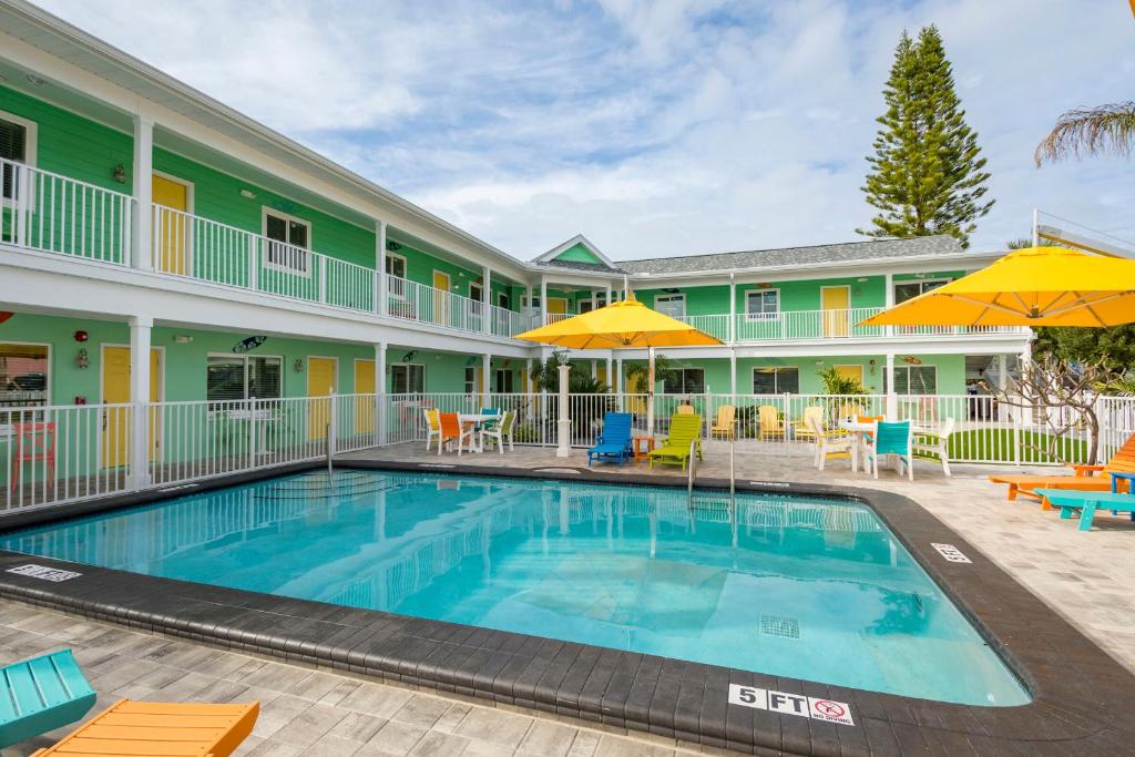 聖彼得海灘的住宿－The Lofts at St Pete Beach，酒店前的游泳池配有椅子和遮阳伞