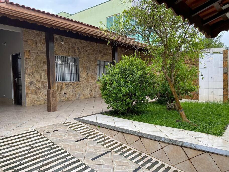 a building with a tree in front of a courtyard at Casa no Centro de Peruibe in Peruíbe
