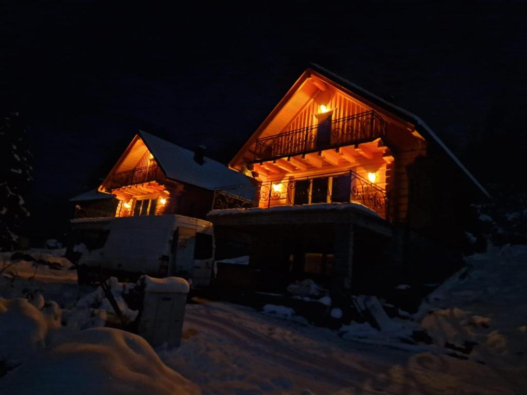 a house with lights on in the snow at night at Domki po balu 