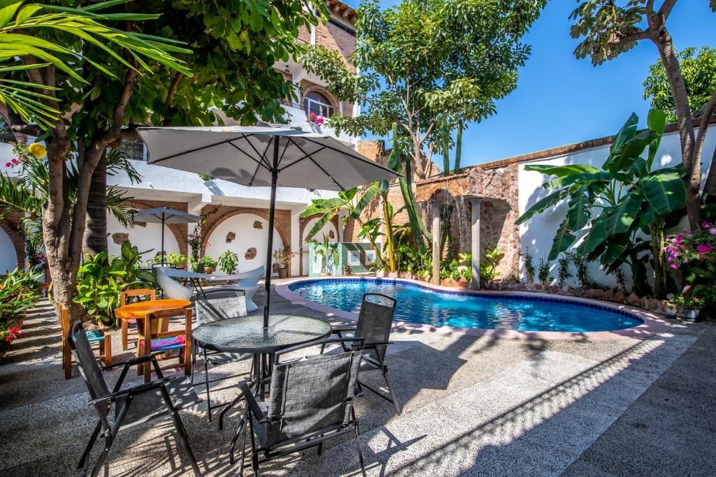 a table with an umbrella next to a swimming pool at Hacienda Lord Twigg - Hotel & Suites in Puerto Vallarta