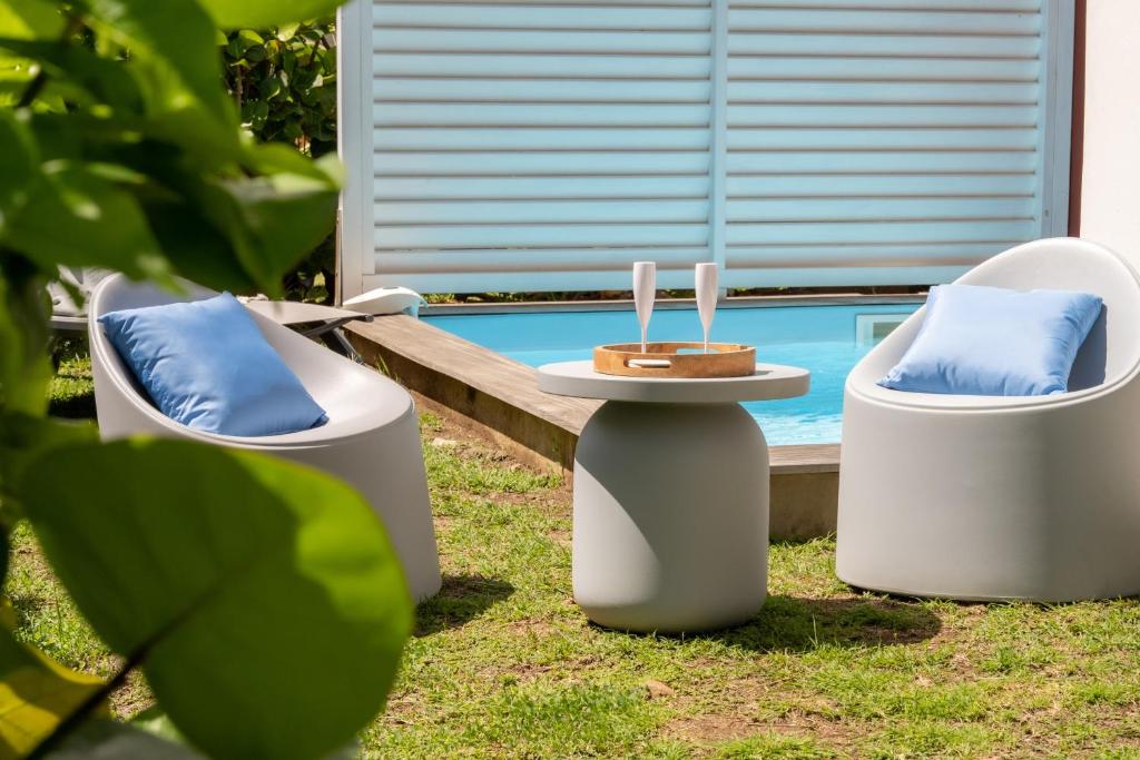 2 Stühle und ein Tisch neben einem Pool in der Unterkunft Villa Physacap in Le François