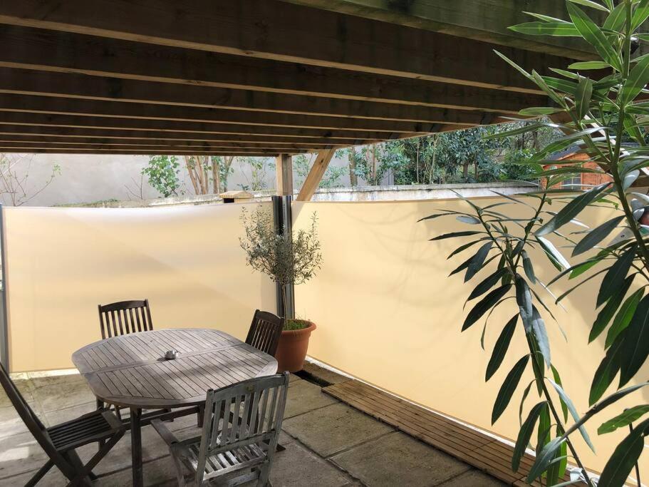 eine Terrasse mit einem Tisch, Stühlen und einem Zaun in der Unterkunft Superbe T2 avec Terrasse face au parc des fontaines in Toulouse
