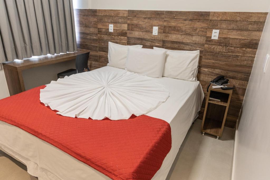 a bedroom with a large bed with a red blanket at Mirante Hotel in Governador Valadares