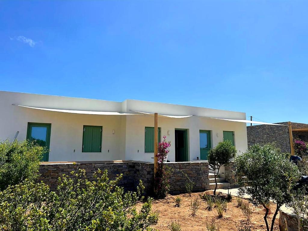 a large house with green windows and a brick wall at Secret Garden - Apartment with jacuzzi in Kampos Paros
