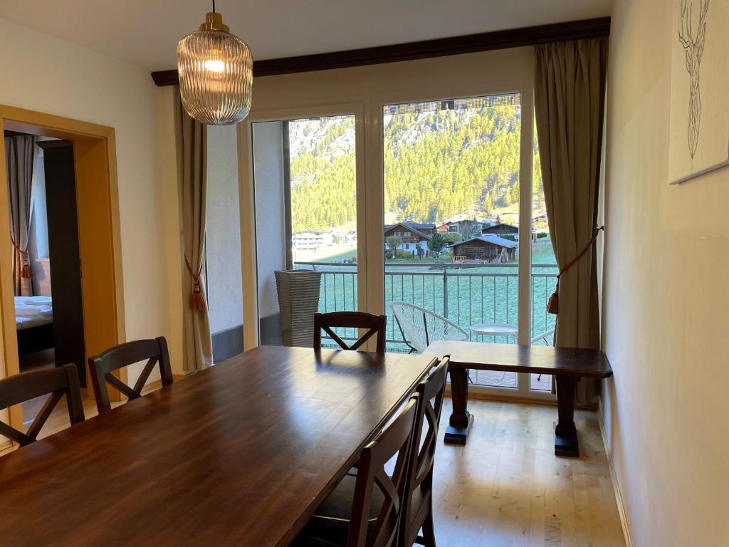 een eetkamer met een tafel en een groot raam bij International House Sölden Apartment mit Blick auf die Berge ZW 8 in Sölden