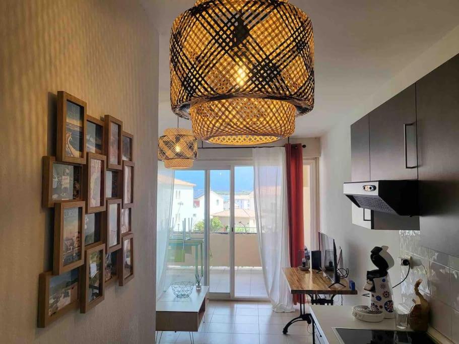 eine Küche mit einem Kronleuchter und ein Zimmer mit einem Fenster in der Unterkunft Charmant T2 climatisé proche Calvi centre in Calvi