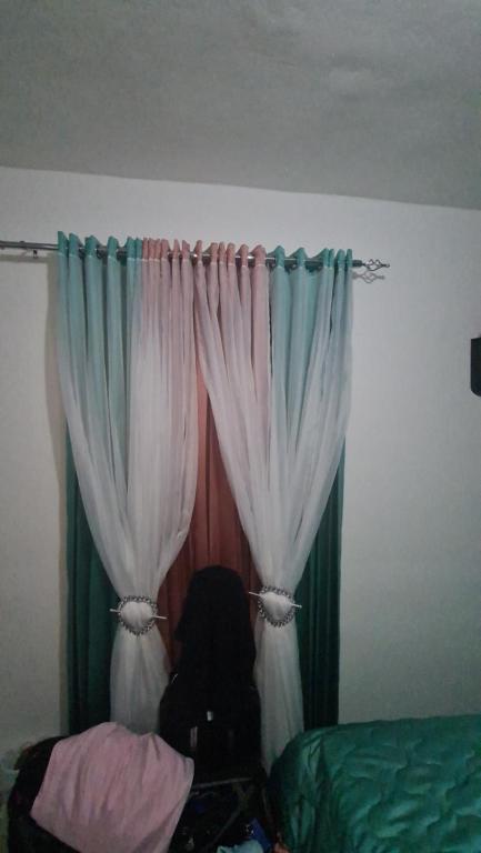 a person sitting in front of a bed with curtains at Suisse.Ch in San Pedro de Macorís
