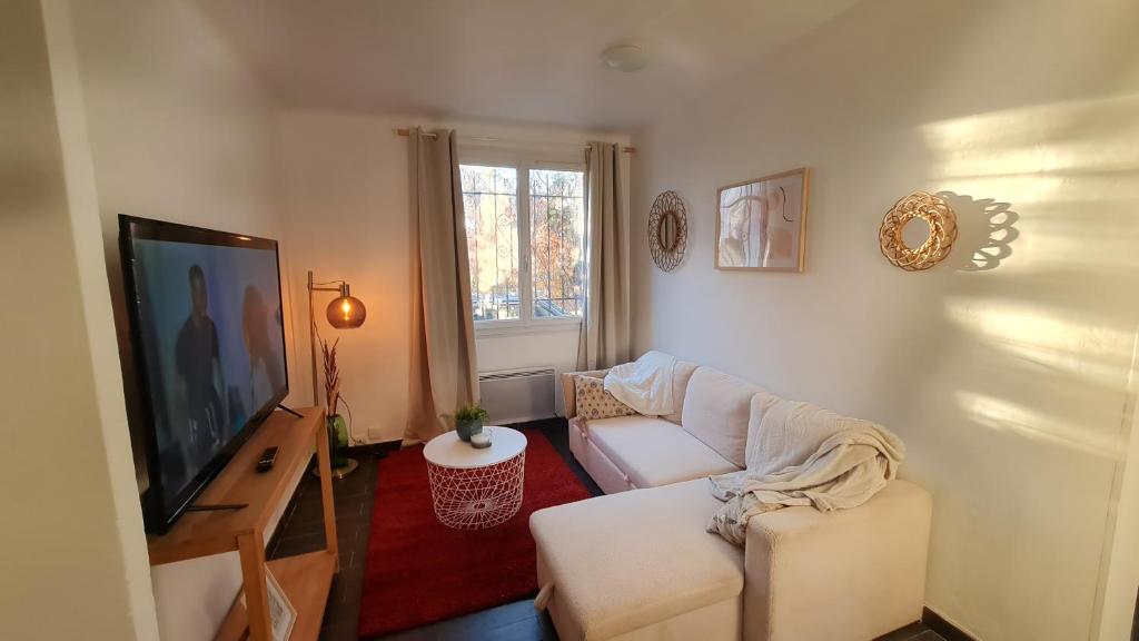 Cocon douillet de Mélanie في مارينيان: غرفة معيشة بها أريكة بيضاء وتلفزيون