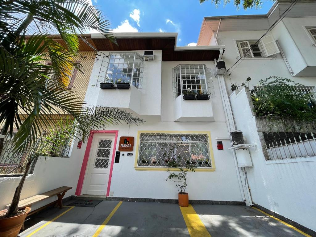 uma casa branca com uma porta rosa e um banco em Morada City Hostel em São Paulo