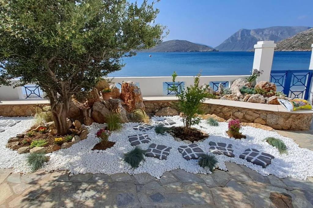 a garden with rocks and plants in front of the water at Aegean Aura Apartment III in Kalymnos
