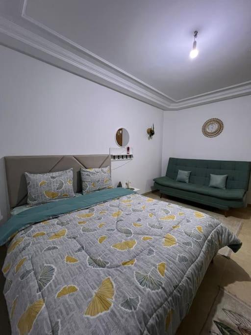 a bedroom with a bed and two green chairs at Cosy studio jardin de l’aouina in Tunis